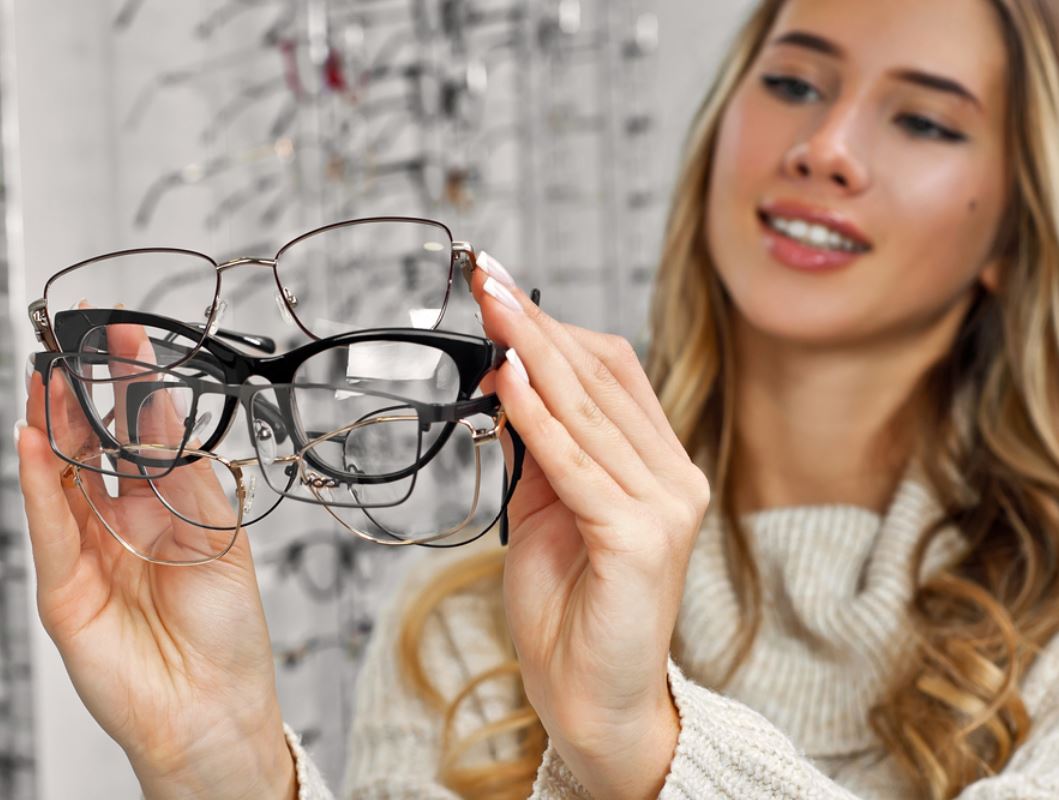 ragazza con tanti occhiali da vista in mano